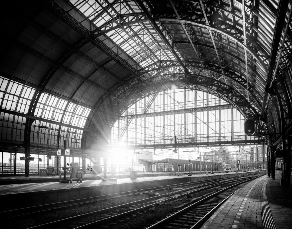 Sonnenaufgang auf einem Bahnhof in Schwarzweiß