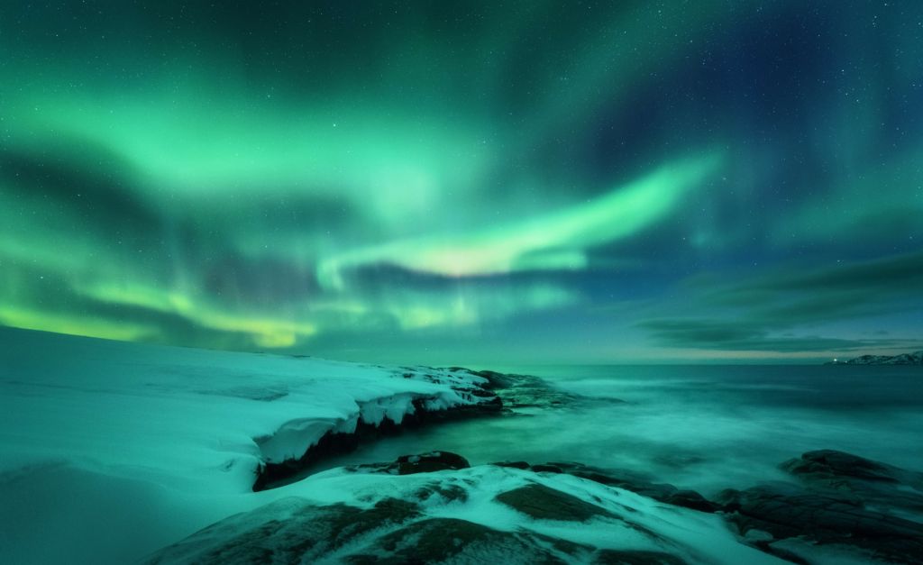 Grünes Nordlicht über verschneiten Felsen